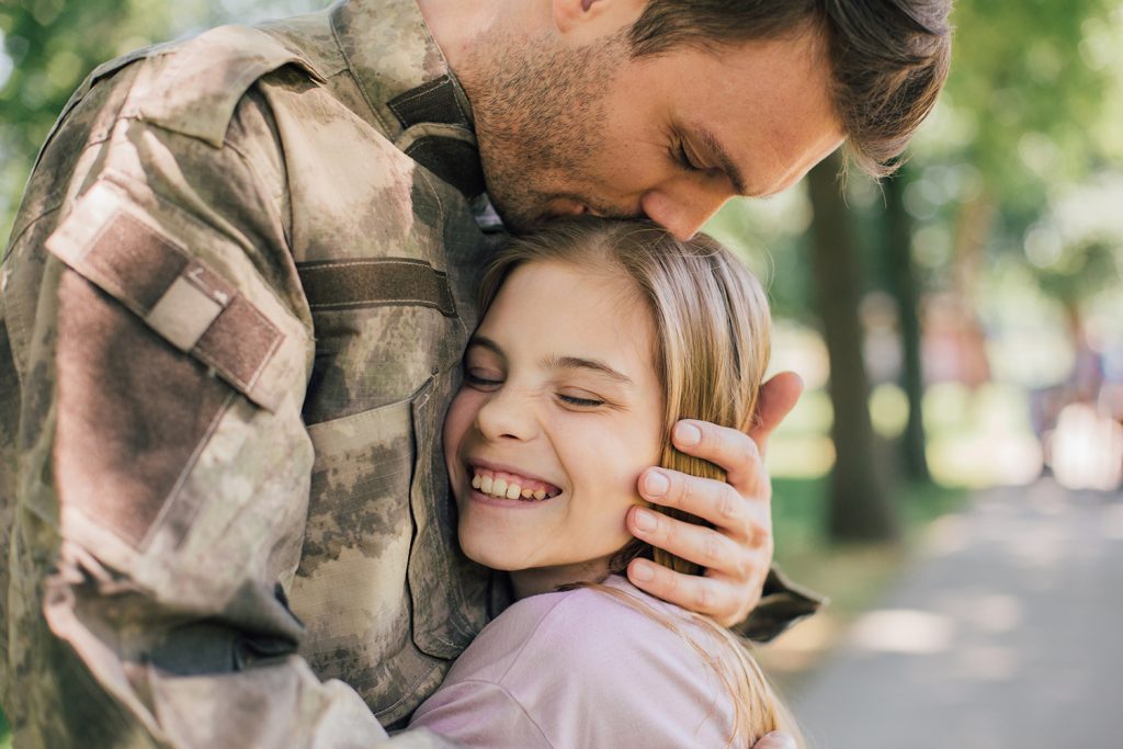 Young military officer hugging and kissing his daughter